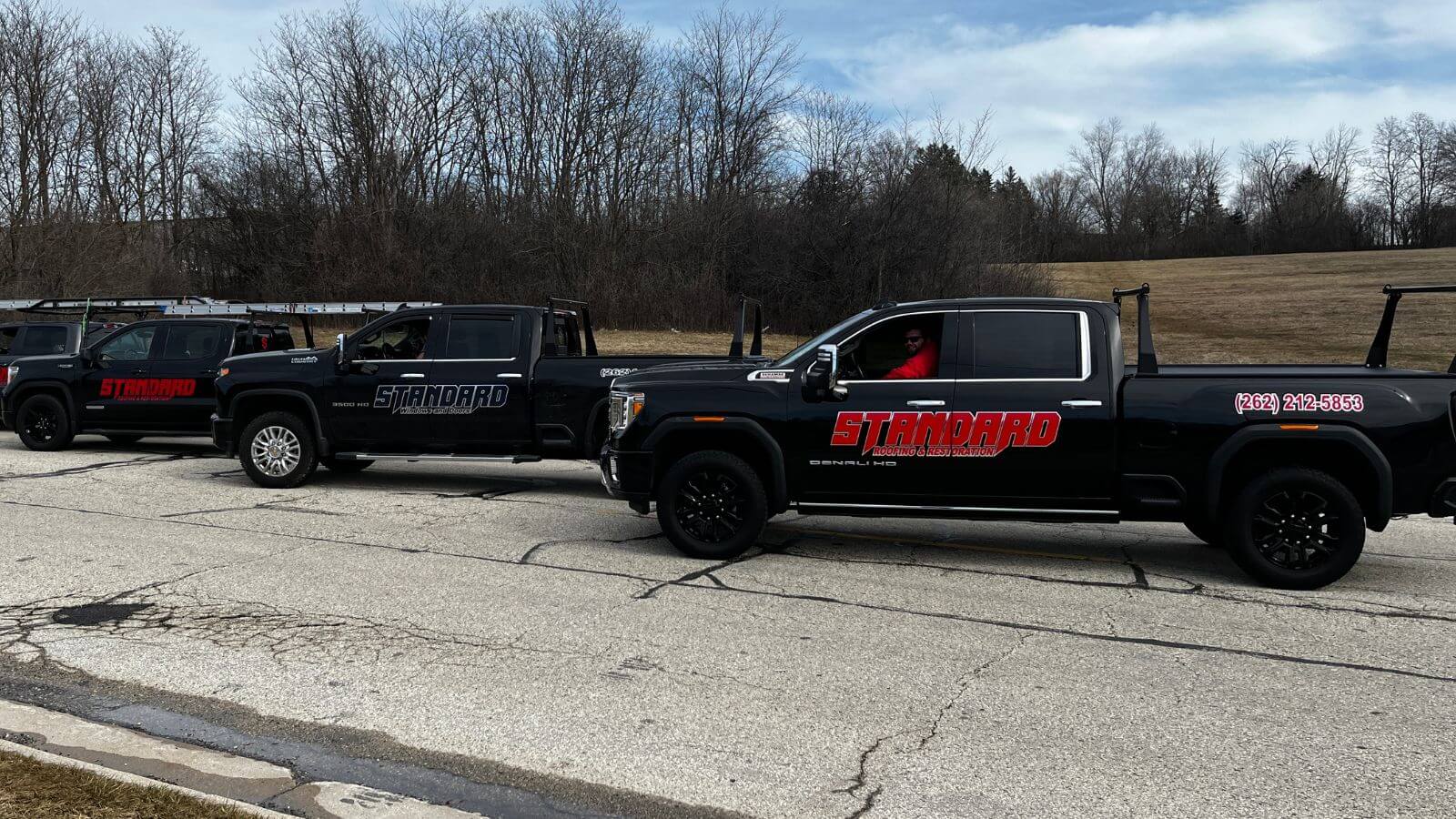 three standard roofing and restoration black trucks