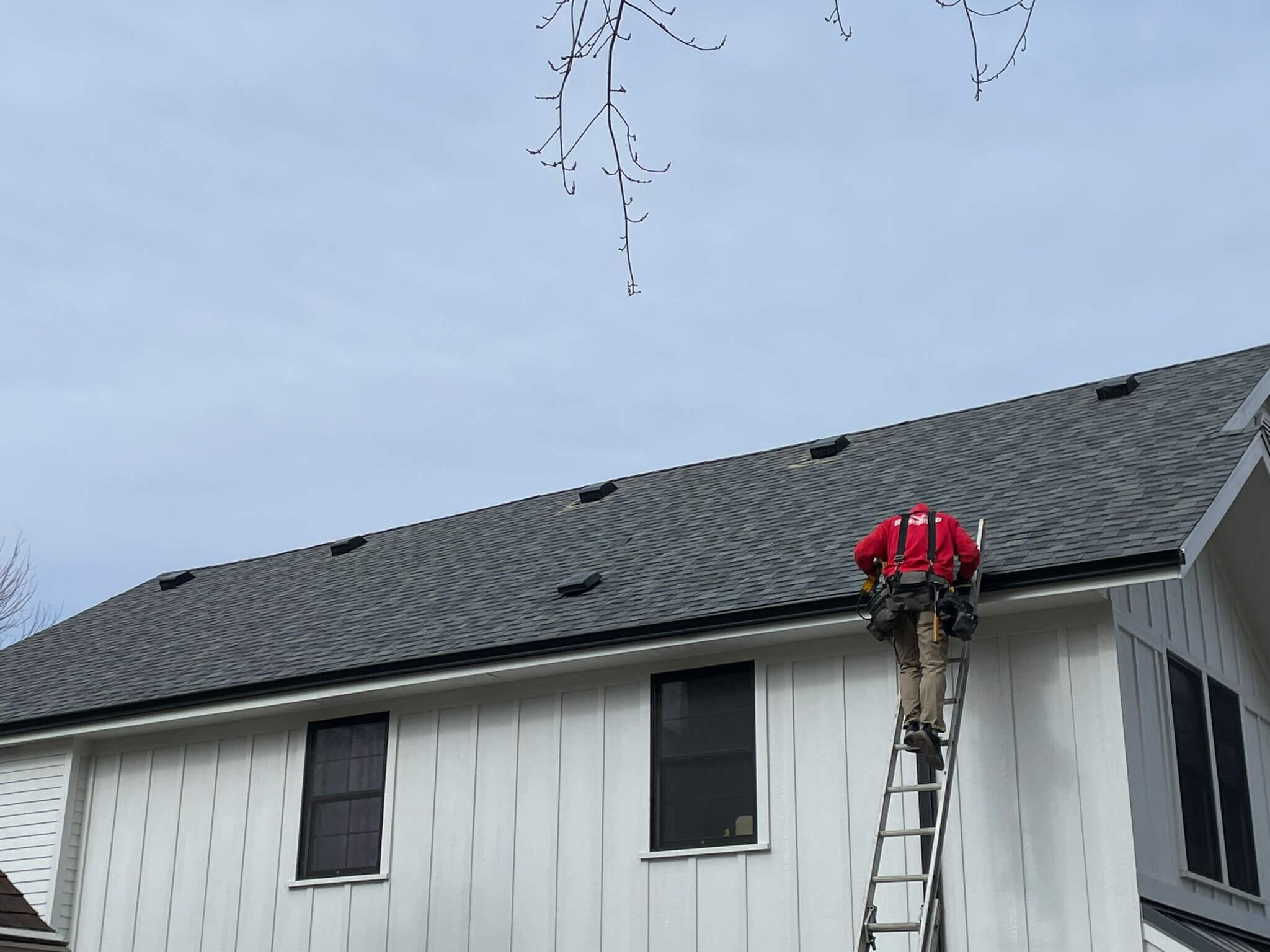 person in red working on a white house with a black roof