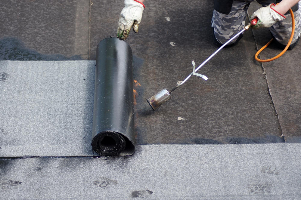 Roofer using a blowtorch to lay down felt roofing
