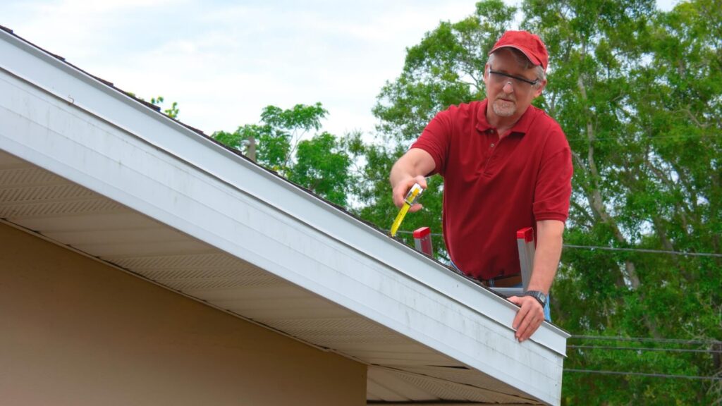 A roof inspector using a tape measure on a roof